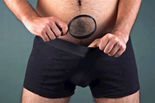a man with a magnifying glass examines his penis and wants to enlarge it